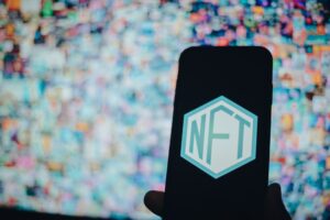 A person holding a mobile phone with an NFT with a desktop wallpaper in the background